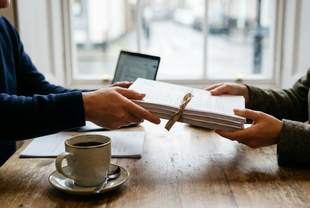 Accountant passing a bound set of finished annual accounts to a client