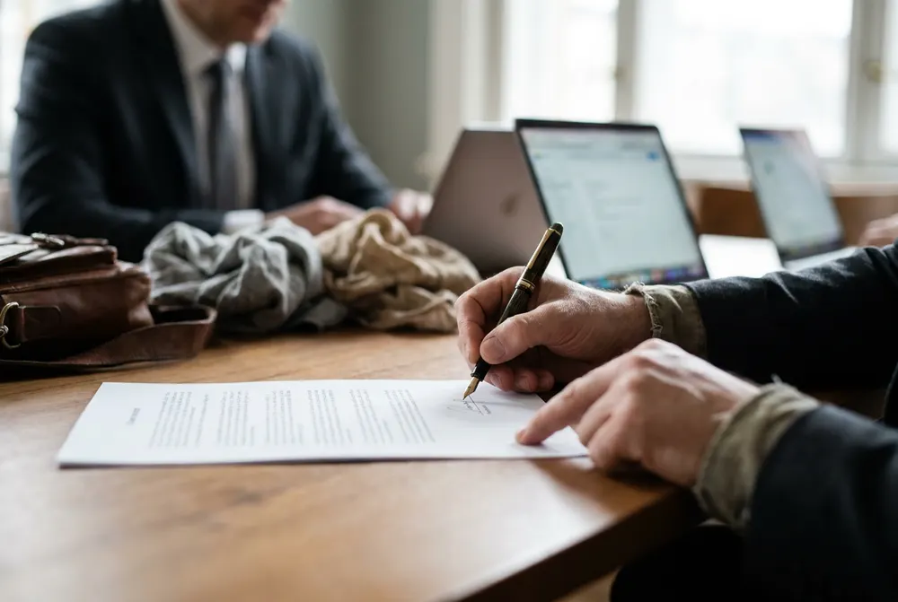 Client signing a letter of engagement at a meeting table
